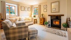 A cozy living room with a sofa, two plaid chairs, a fireplace, and framed pictures on the walls. - Teagles Cottage - a delightful home from home in Stow-on-the-Wold (Cheltenham)