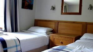 A hotel room with two single beds, a wooden nightstand, a mirror, and a painting on the wall. - Cottage 9 -  a cottages  that sleeps 6 guests  in 0 bedrooms (Irvinestown)