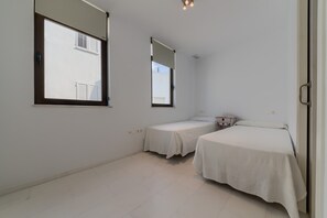 Un dormitorio con dos camas, una ventana, un espejo y una mesita de noche.