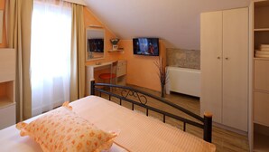 Un dormitorio con cama, escritorio, televisor y armario.