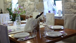 Una mesa de comedor con platos blancos, copas de vino y una botella de vino.