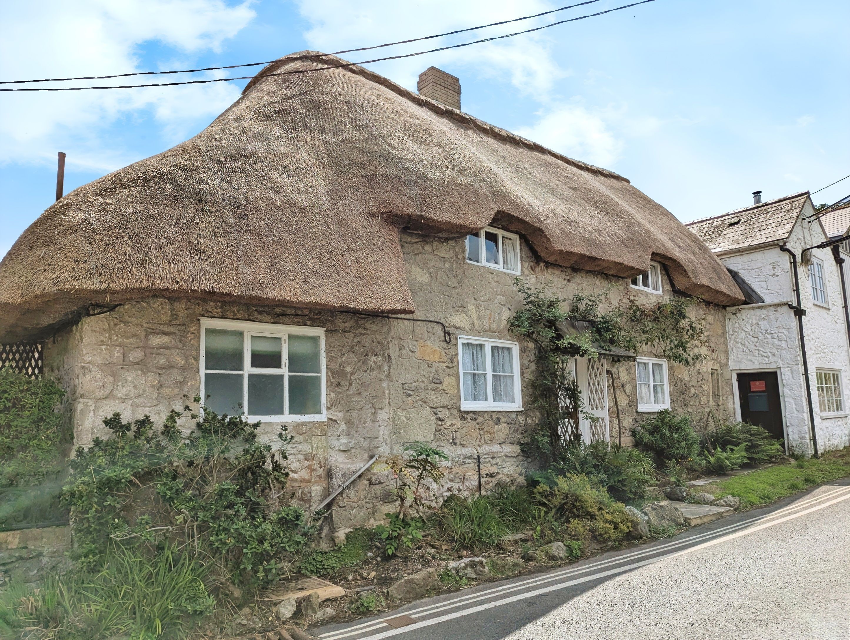 A traditional stone house with a thatched roof and multiple windows.