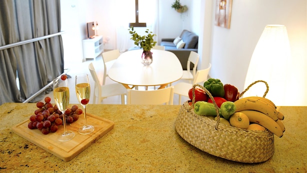 A kitchen counter with a fruit basket, a cutting board with grapes, and two glasses of white wine. - Spacious apartment in the Center of Palma, Ideal for Families. (Palma)