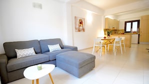 A modern living room with a grey sectional sofa, a white coffee table, and a dining area with white chairs. - Spacious apartment in the Center of Palma, Ideal for Families. (Palma)