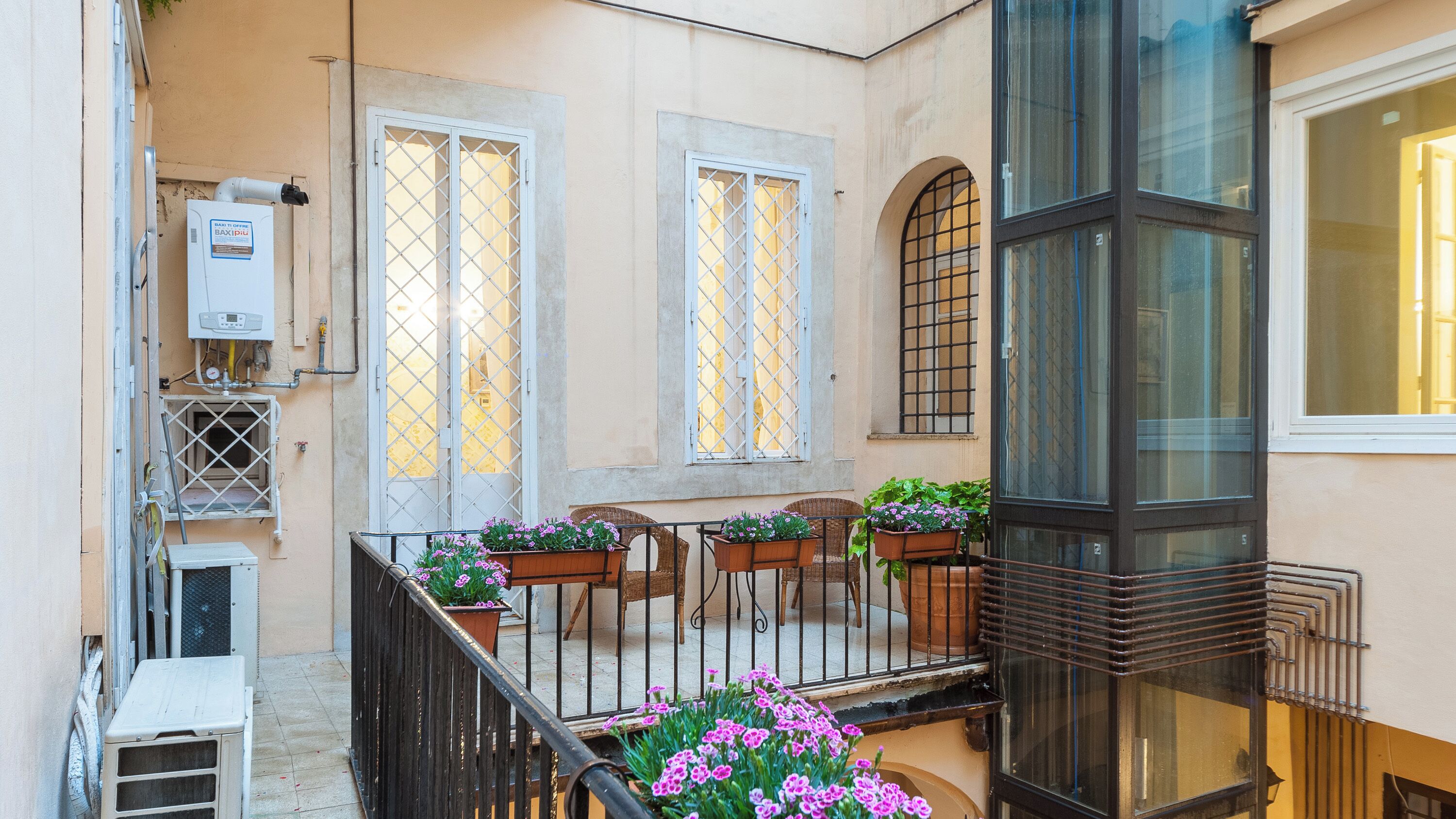 A balcony with potted plants, a railing, and a view of the street.