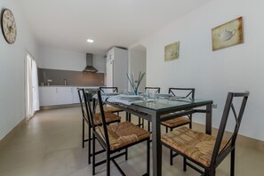 Een eetgedeelte met een glazen tafel, zwarte stoelen en een keuken op de achtergrond.