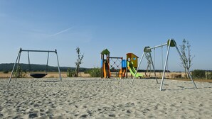 A playground with swings and climbing structures on a sandy beach.