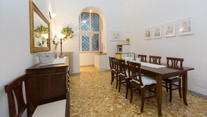 A dining area with a mosaic floor, wooden furniture, a large window with a view, and wall-mounted artwork.