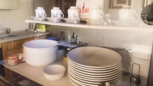 Een keuken met een stapel witte borden, kommen en een koffiezetapparaat op het aanrecht.