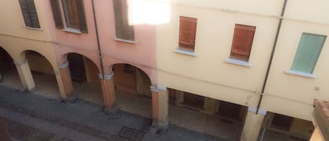 A multi-story building with balconies, arched doorways, and a series of windows with shutters.
