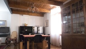 Een eethoek met een houten tafel en stoelen, een televisie en een koelkast.