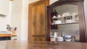Een keuken met een houten deur, een marmeren aanrechtblad en een kast met servies.