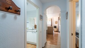 A hallway leading to a kitchen with white cabinets, a sink, and a dining area with a sofa and table. - Las Dunas - Punta del Moral Beach PLHD141P160 (Punta del Moral)