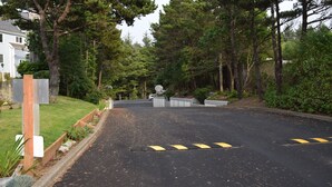A residential driveway with a gated entrance, surrounded by tall trees and a well-maintained lawn. - Schooner Landing (Newport)
