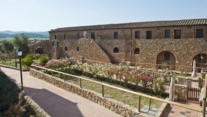 A stone building with arched windows and a tiled roof, surrounded by a stone wall and a paved walkway. - Beautiful apartment for 5 people with pool, A/C, TV and panoramic view (Casalappi)