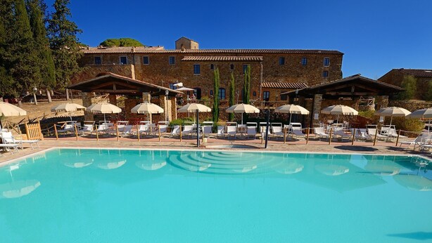 A pool area with lounge chairs and umbrellas, surrounded by stone buildings. - Beautiful apartment for 5 people with pool, A/C, TV and panoramic view (Casalappi)