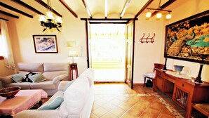 A living room with a sofa, a dining table, and a kitchen area with a cabinet and a painting on the wall. - Finca Vicente - charming, Spanish finca style holiday villa in Teulada (Teulada)