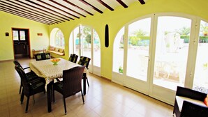 A dining area with a table and chairs, large arched windows, and a ceiling with wooden beams. - Finca Vicente - charming, Spanish finca style holiday villa in Teulada (Teulada)
