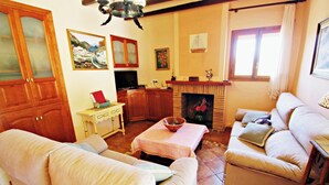 A living room with a sofa, a coffee table, a fireplace, and wooden cabinets. - Finca Vicente - charming, Spanish finca style holiday villa in Teulada (Teulada)