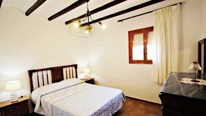 A bedroom with a wooden bed, two bedside tables with lamps, a window with curtains, and a wooden dresser. - Finca Vicente - charming, Spanish finca style holiday villa in Teulada (Teulada)