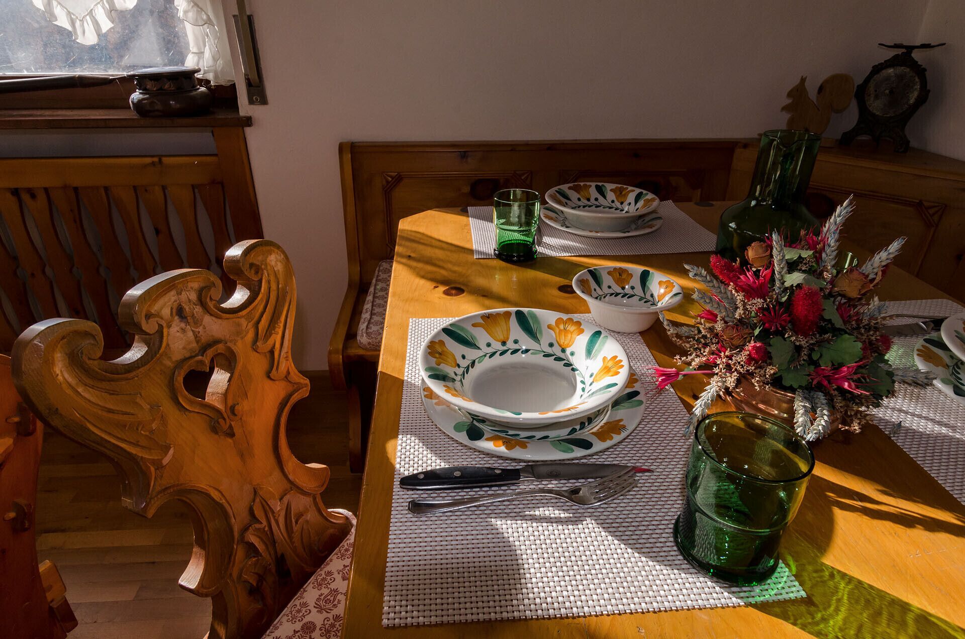 Ein Esstisch mit Tellern, Besteck und einer Blumenvase.
