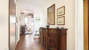 Un couloir avec une armoire en bois, un miroir et des tableaux encadrés accrochés au mur.