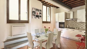 Une cuisine moderne avec des meubles blancs, un pare-feu en carrelage et un coin repas avec une table blanche dressée pour quatre personnes.