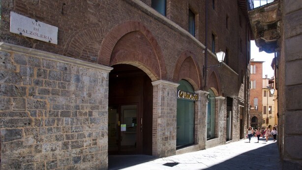 A stone building with a sign reading "VIA DI CALZOLERIA". - THE TOLOMEI - apartment in the heart of the main street (Siena)