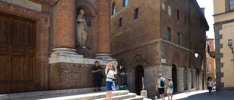 A historic building with a statue on the steps, a wooden door, and a brick facade.
