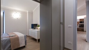 A modern bedroom with a bed, bedside table, and a wall-mounted light fixture. - THE TOLOMEI - apartment in the heart of the main street (Siena)