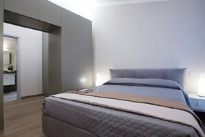 A modern bedroom with a large bed, a bedside table, and a nightstand. - IL TOLOMEI - new apartment in the middle of the main street (Siena)