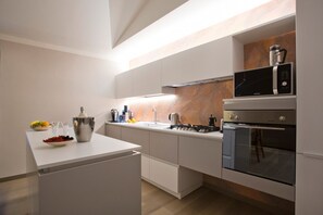 A modern kitchen with a white countertop, stainless steel appliances, and a wooden backsplash. - IL TOLOMEI - new apartment in the middle of the main street (Siena)