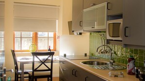 Eine moderne Küche mit Edelstahlgeräten, ein Essbereich mit Tisch und Stühlen sowie ein Fenster mit Jalousien.