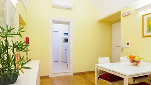 A compact living space with a dining area, a doorway leading to a kitchen, and a potted plant.