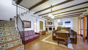 A spacious living room with a wooden staircase, a dining area, and a fireplace. - Wonderful private villa for 8 people with private pool, WIFI, A/C and TV (Marina Di Ragusa)