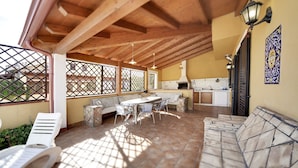 A covered patio with a dining table, chairs, and a sofa. There is a kitchen area with a stove and sink. - Wonderful private villa for 8 people with private pool, WIFI, A/C and TV (Marina Di Ragusa)