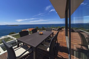 Une terrasse avec une table et des chaises offrant une vue sur la côte.