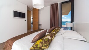 A hotel room with a large bed, a TV mounted on the wall, and a view of the sea through the window. - Luxury Apartment the Ocean Dream V (Primošten)