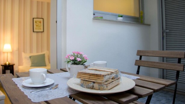Une table en bois sur laquelle se trouvent une assiette blanche remplie de sandwichs, une tasse blanche et un vase de fleurs.
