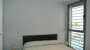 Une chambre à coucher avec un lit, une table de chevet, une lampe et une fenêtre avec des stores.