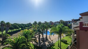 A resort with a swimming pool surrounded by palm trees and a clear blue sky.