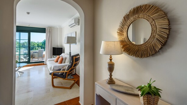 A modern living room with a sofa, armchair, and a lamp on a console table.