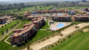 An aerial view of a residential area with multi-story buildings, a swimming pool, and a golf course.