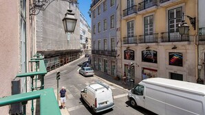 Una calle estrecha flanqueada por edificios, una camioneta blanca y un autobús blanco.