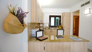 Una cocina moderna con armarios de madera, encimera de granito, cafetera y una planta colgante.