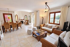 A spacious living area with a dining set, sofas, and a television. - Chrisuli - well furnished villa with panoramic views in Moraira (Benimeit)