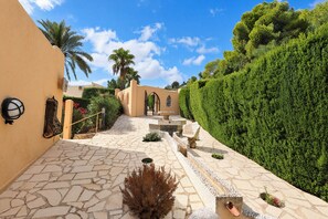 A stone pathway leading to a gated entrance with a palm tree and a hedge on one side. - Chrisuli - well furnished villa with panoramic views in Moraira (Benimeit)