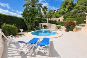 A pool area with lounge chairs and a stone wall. - Chrisuli - well furnished villa with panoramic views in Moraira (Benimeit)