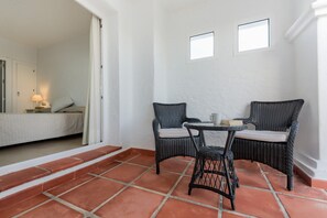 A room with a bed, a small table with chairs, and a window.