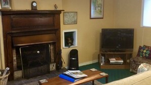 A living room with a fireplace, a television, and a sofa. - Pond Cottage, Carmichael Country Cottages. Pets welcome. (Biggar)